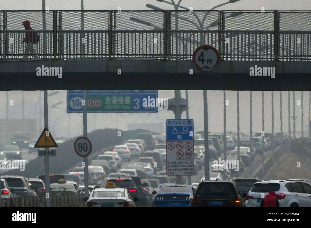 A resident walks across a pedestrian overhead bridge as motorists ...