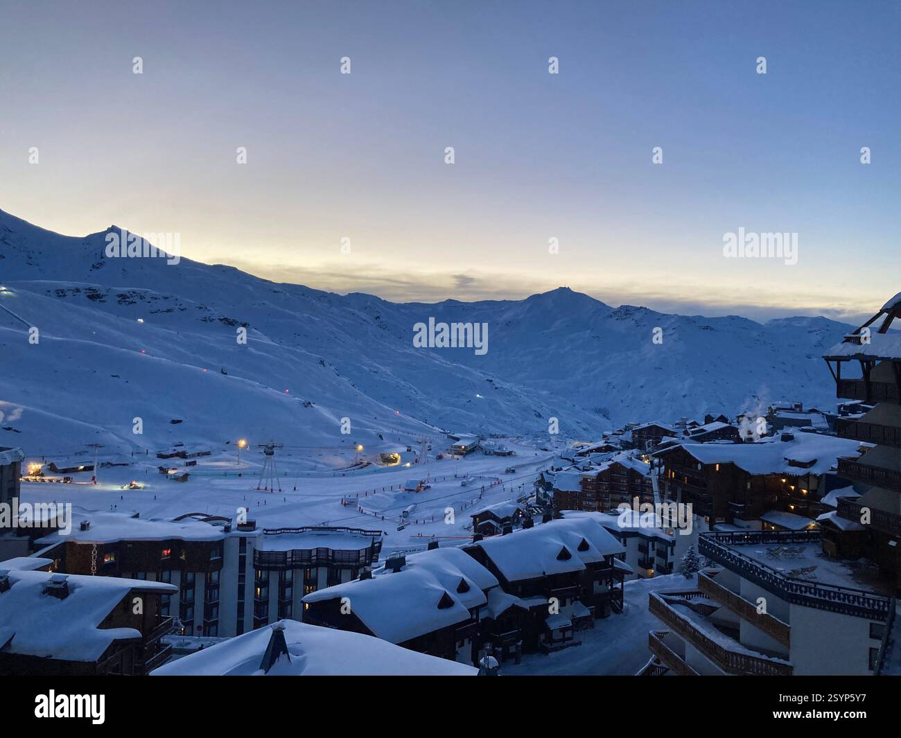 Val Thorens at dusk: ski chalets glow under a clear evening sky, contrasting beautifully with the pristine snow and peaceful resort atmosphere. - Smartphone Captured Stock Image