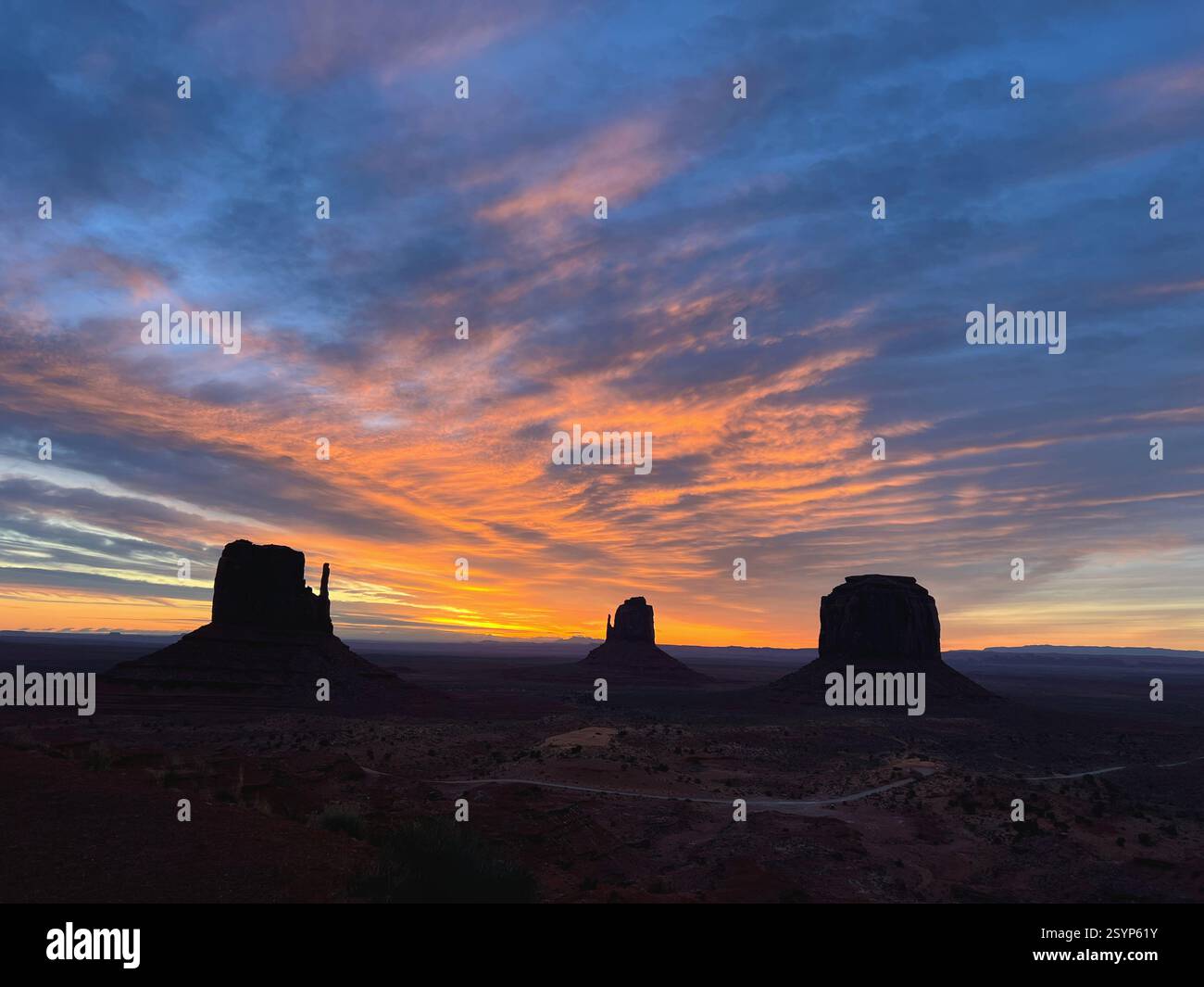 Sunrise paints Monument Valley’s sky in orange and violet as its iconic monoliths slowly emerge from the shadows of the vast desert. - Smartphone Captured Stock Image