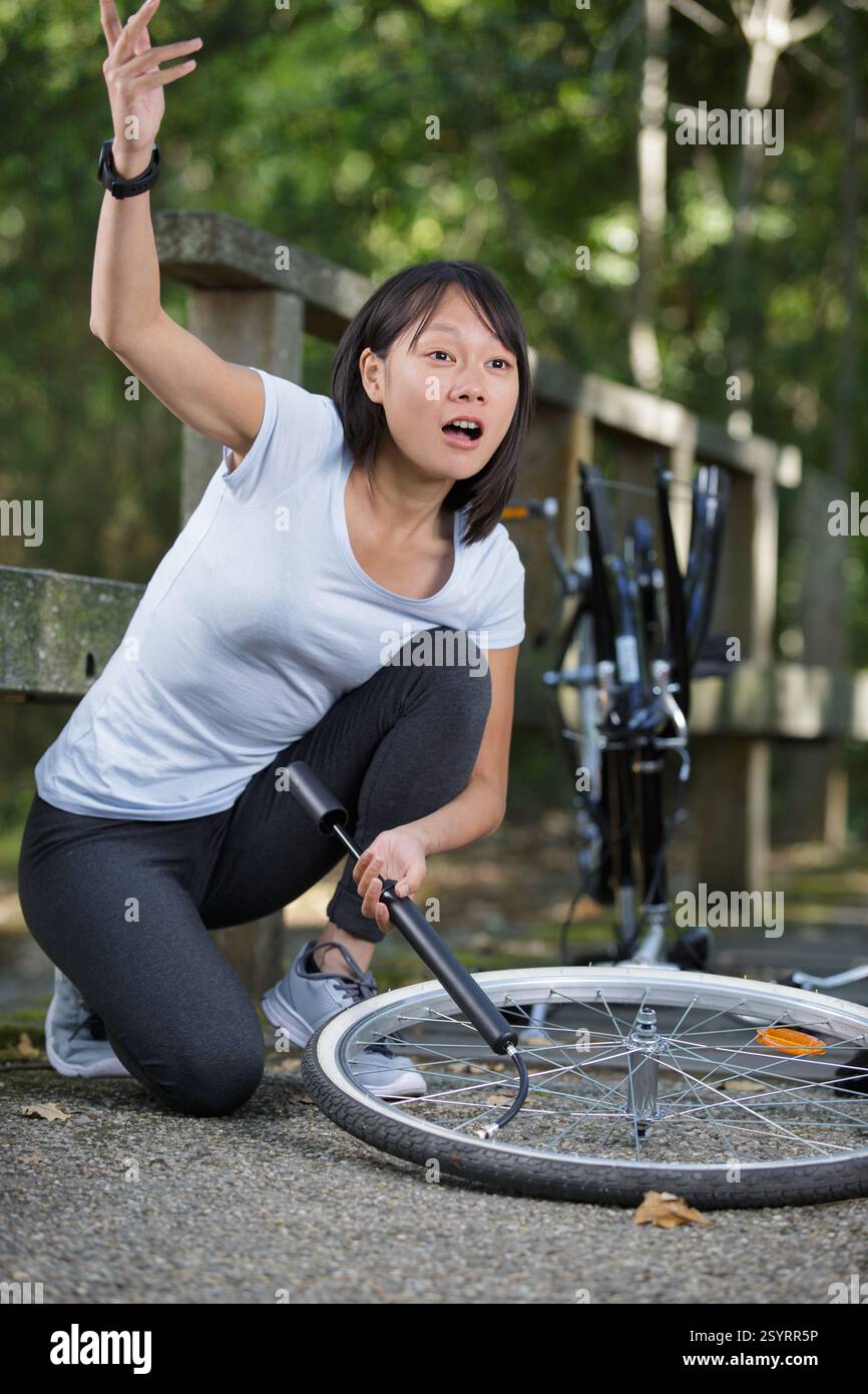 Pumping Up stressed woman pumping up a bike tyre Stock Photo - Alamy