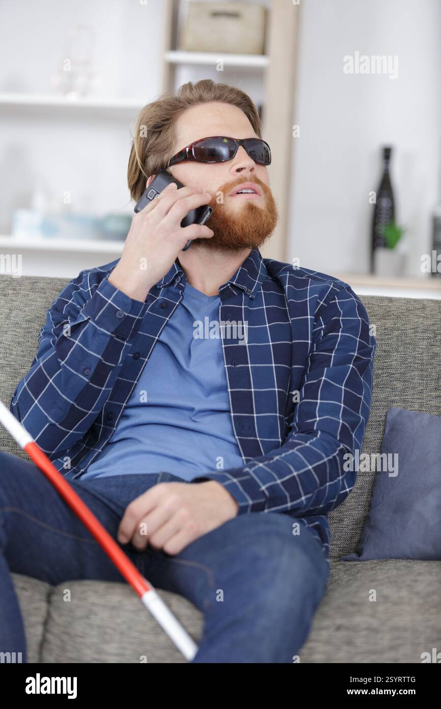 visually impaired man on the sofa using a telephone Stock Photo