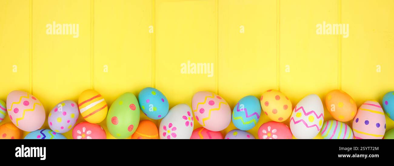 Colorful Easter Egg bottom border over a bright yellow wood banner background. Copy space. Stock Photo