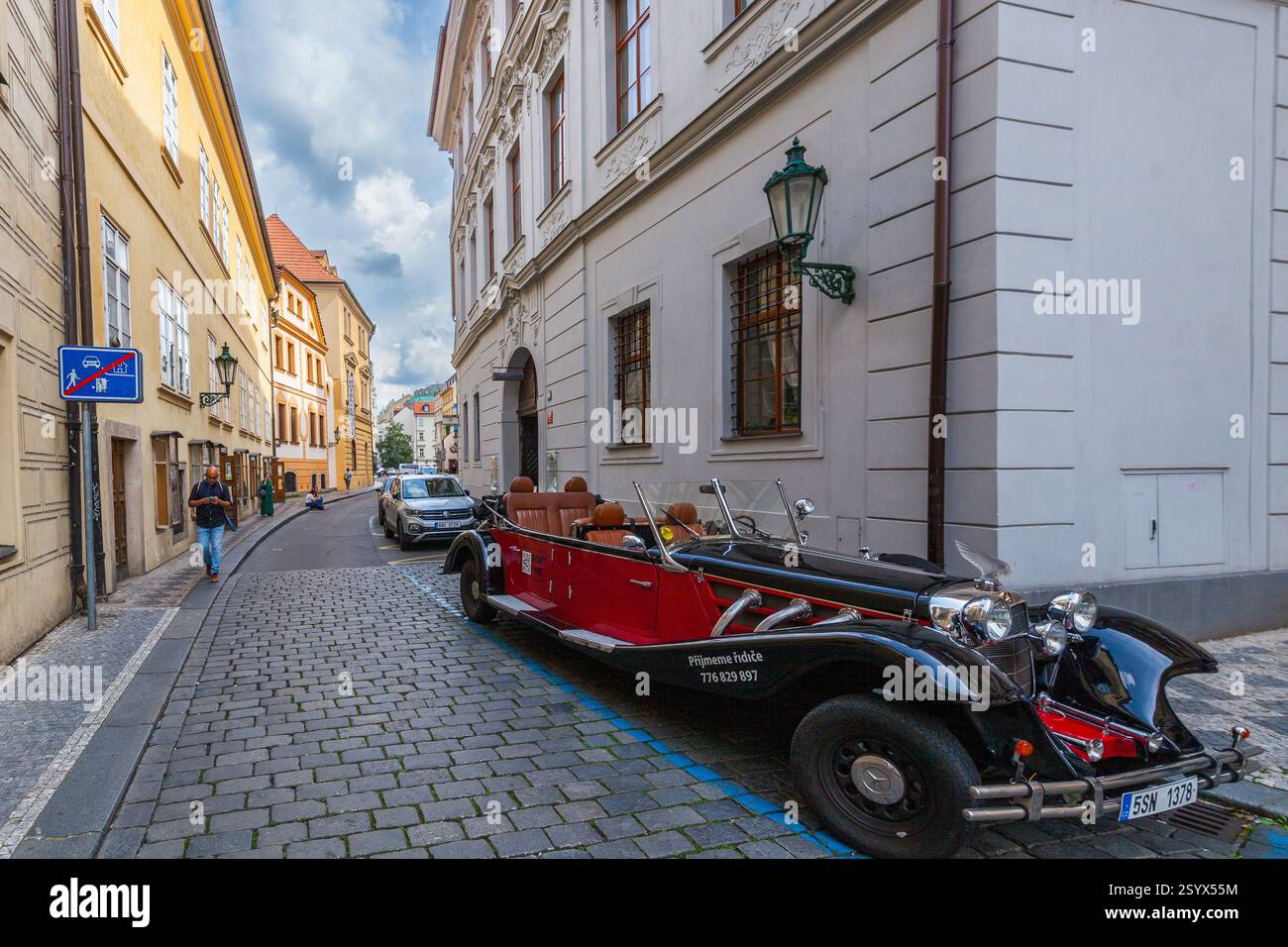 A vintage red and black convertible car is parked on a cobblestone ...