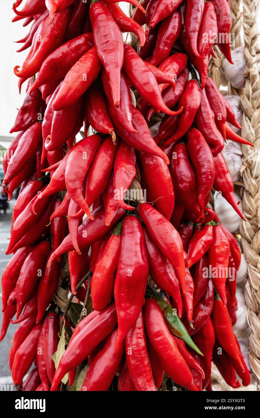 Bunches of dried peppers hang on a open air market stall. Red hot ...