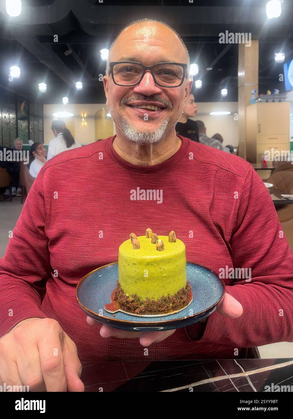 Adult man holding a pistachio cake dessert in a Turkish style restaurant, Toronto, Canada Stock Photo