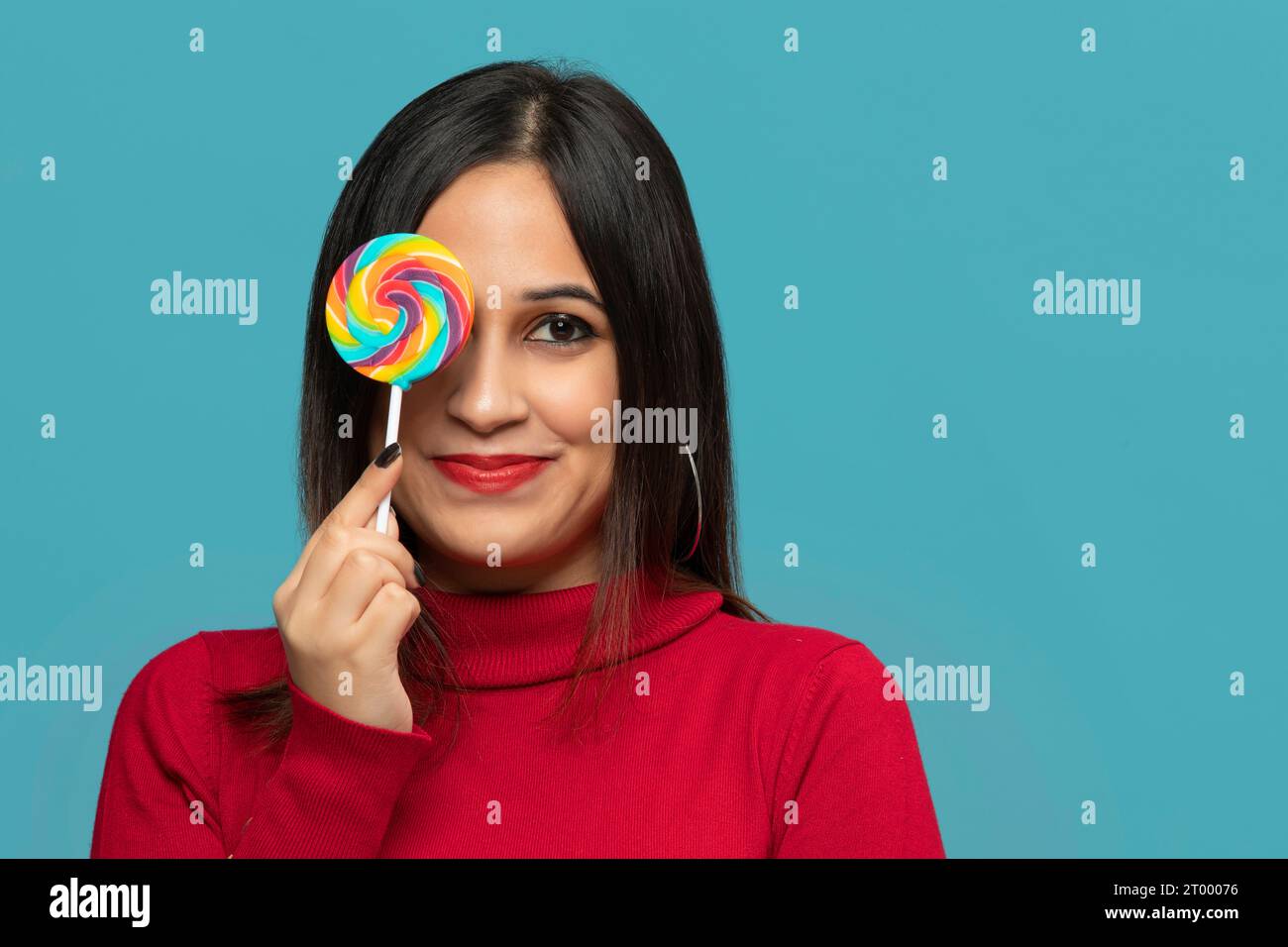 young woman covering eye with lollipop and smiling Stock Photo