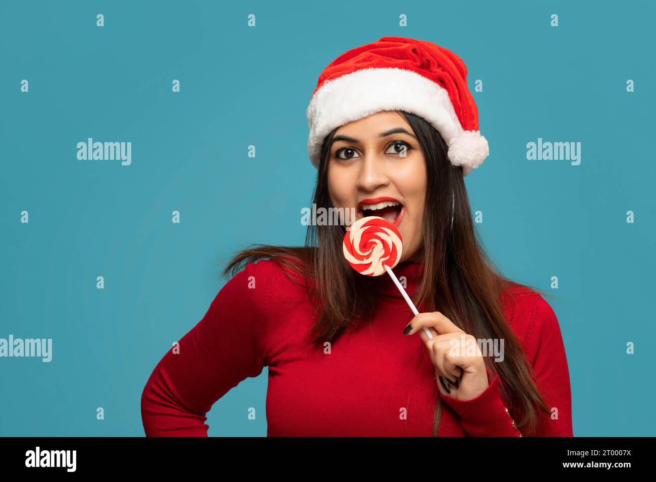 Young woman eating a lollipop on a blue background Stock Photo