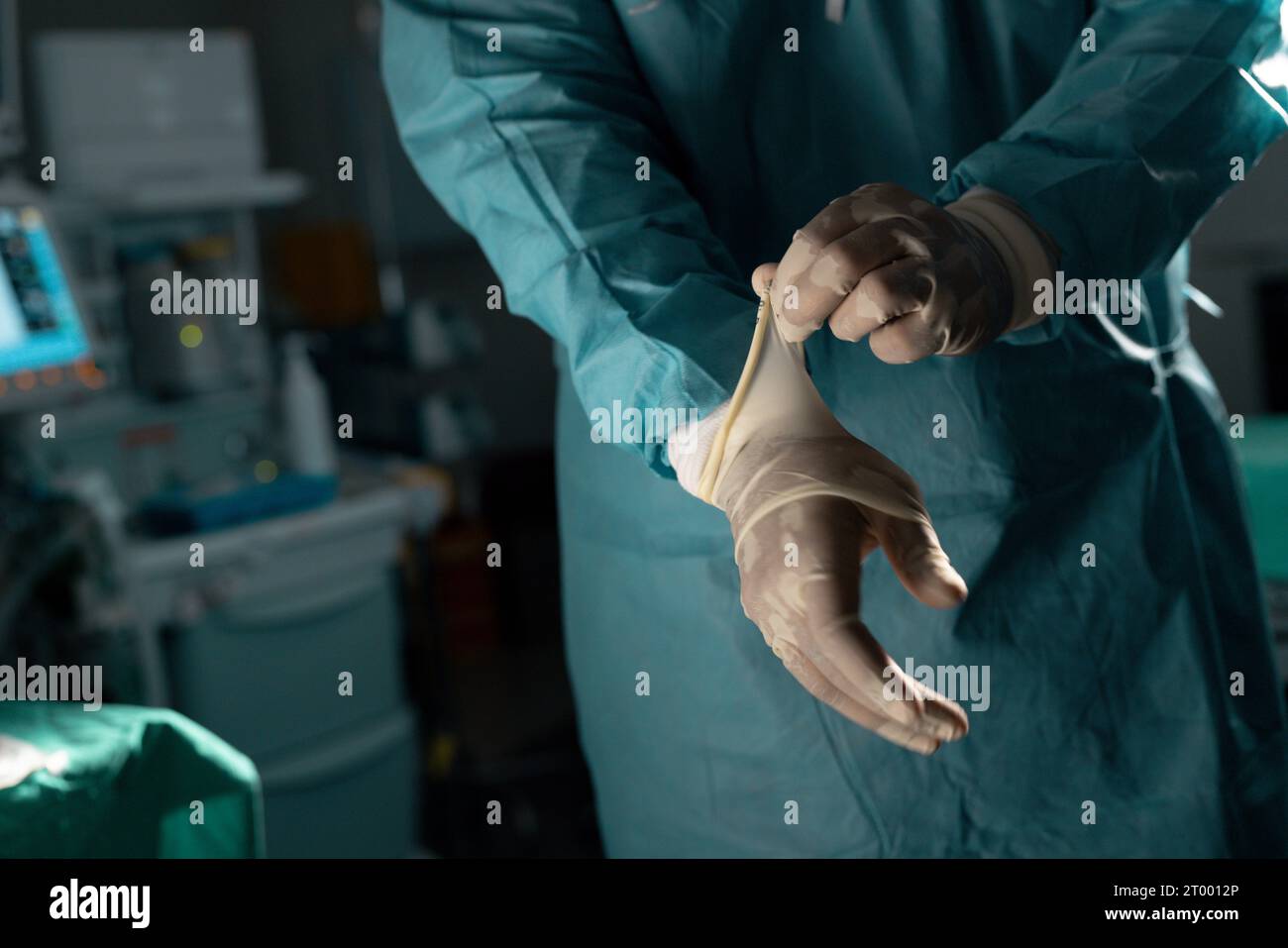 Midsection of biracial male surgeon wearing surgical gown and gloves in