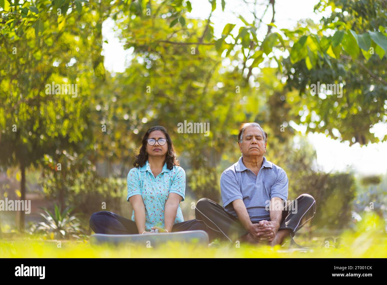 Mature couple doing yoga in public park Stock Photo