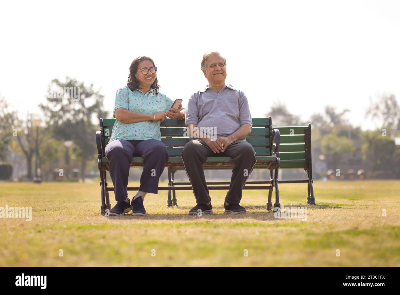 Happy Mature couple sitting together on a bench in public park Stock Photo
