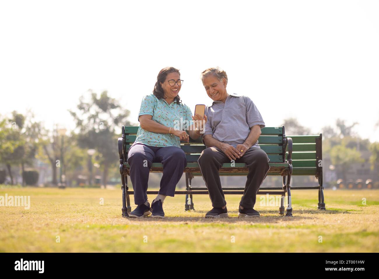 Happy Mature couple using mobile phone while sitting together on a ...
