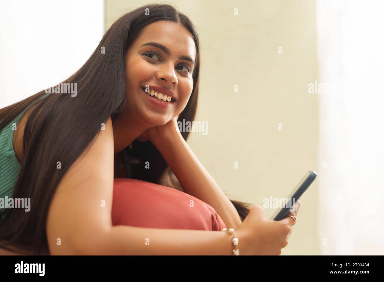 Close-up portrait of young woman using mobile phone while relaxing in hotel room Stock Photo