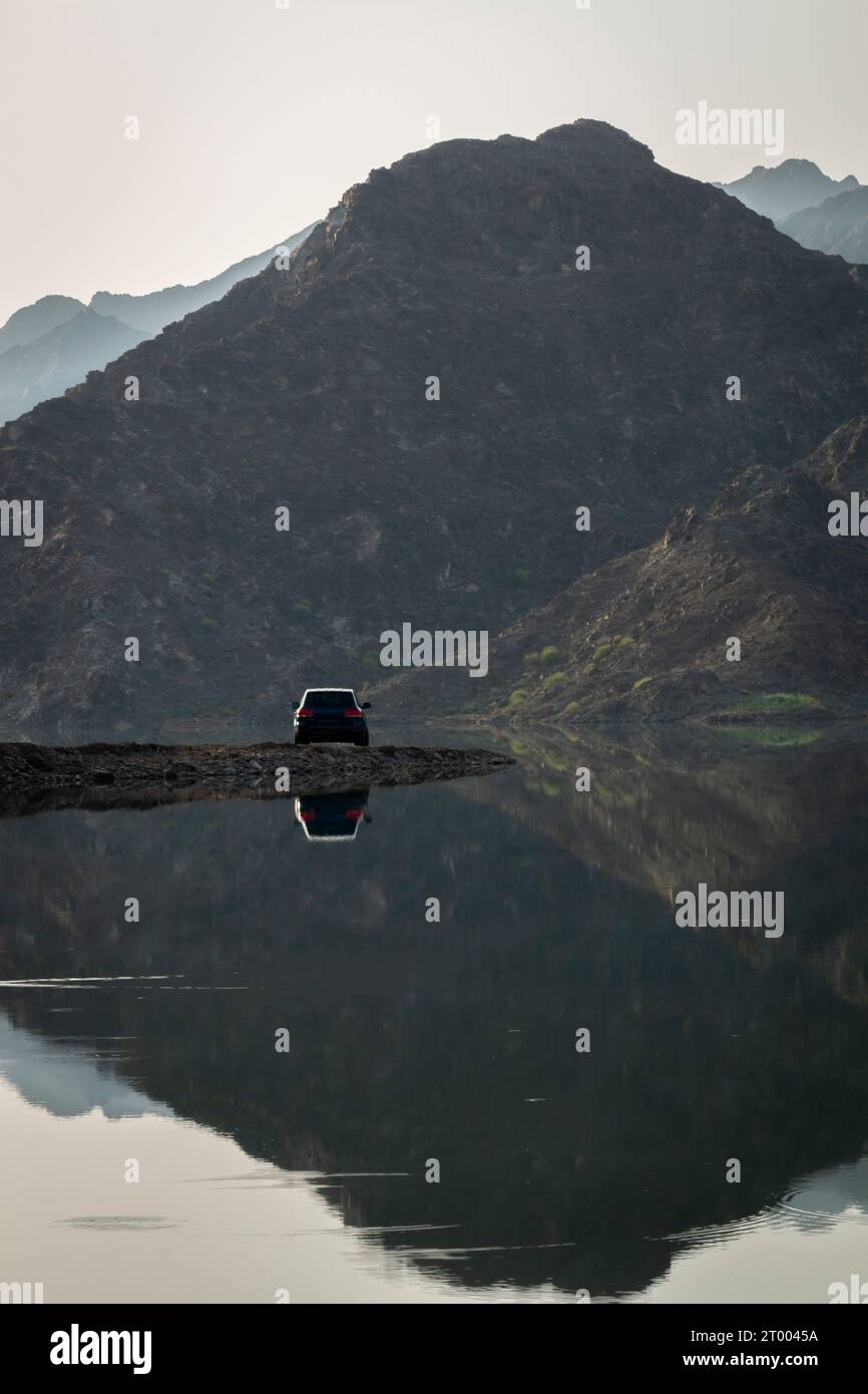 Four wheel drive car parked near the lake with huge mountains in the background. Stock Photo