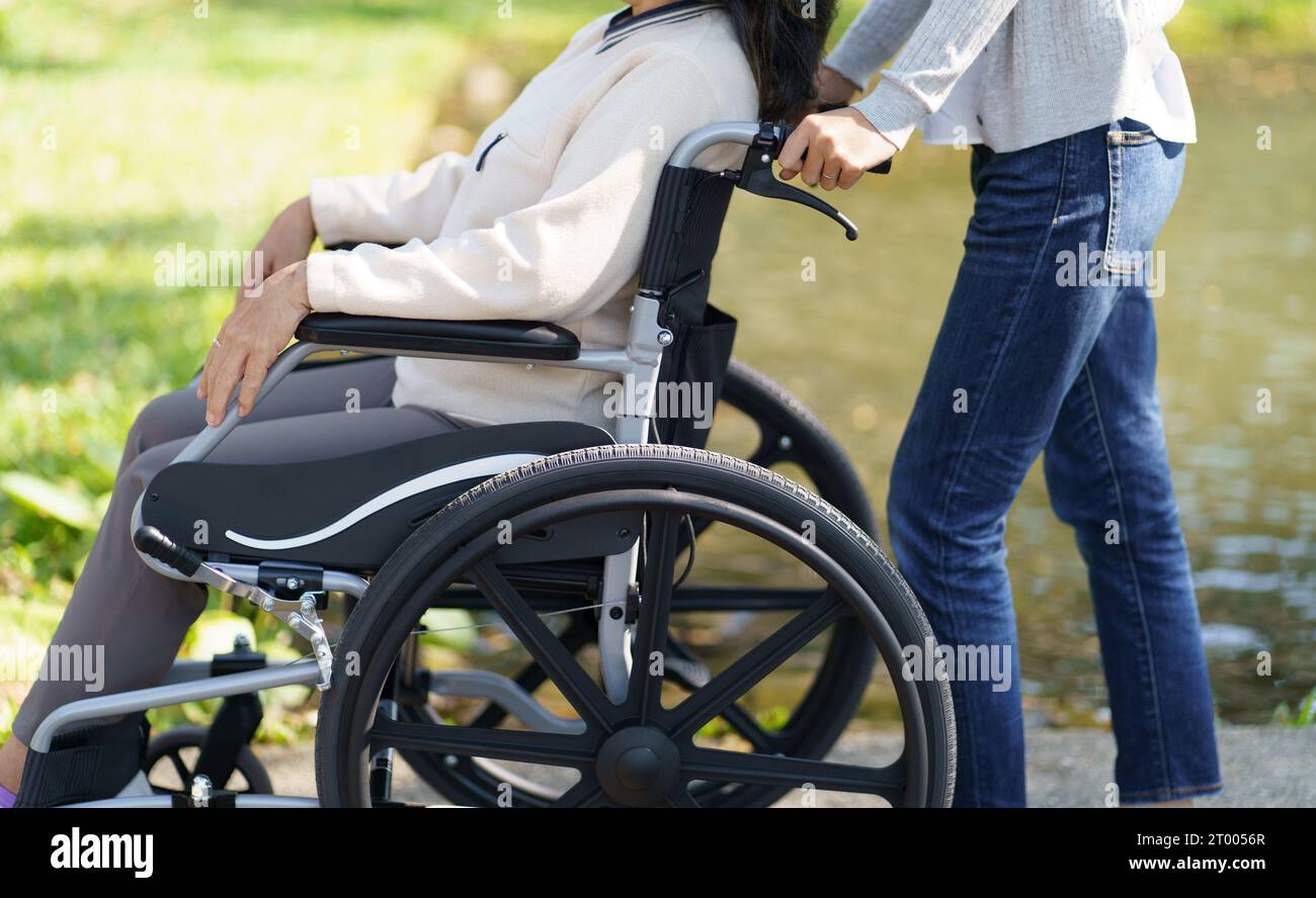 Nursing home. Young caregiver helping senior woman in wheelchair. Stock Photo