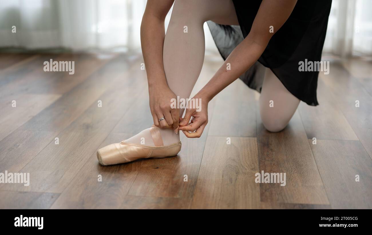 Close up view of young girl puts on ballet shoes on her feet before training for a dance class at home. ballet concept. Stock Photo