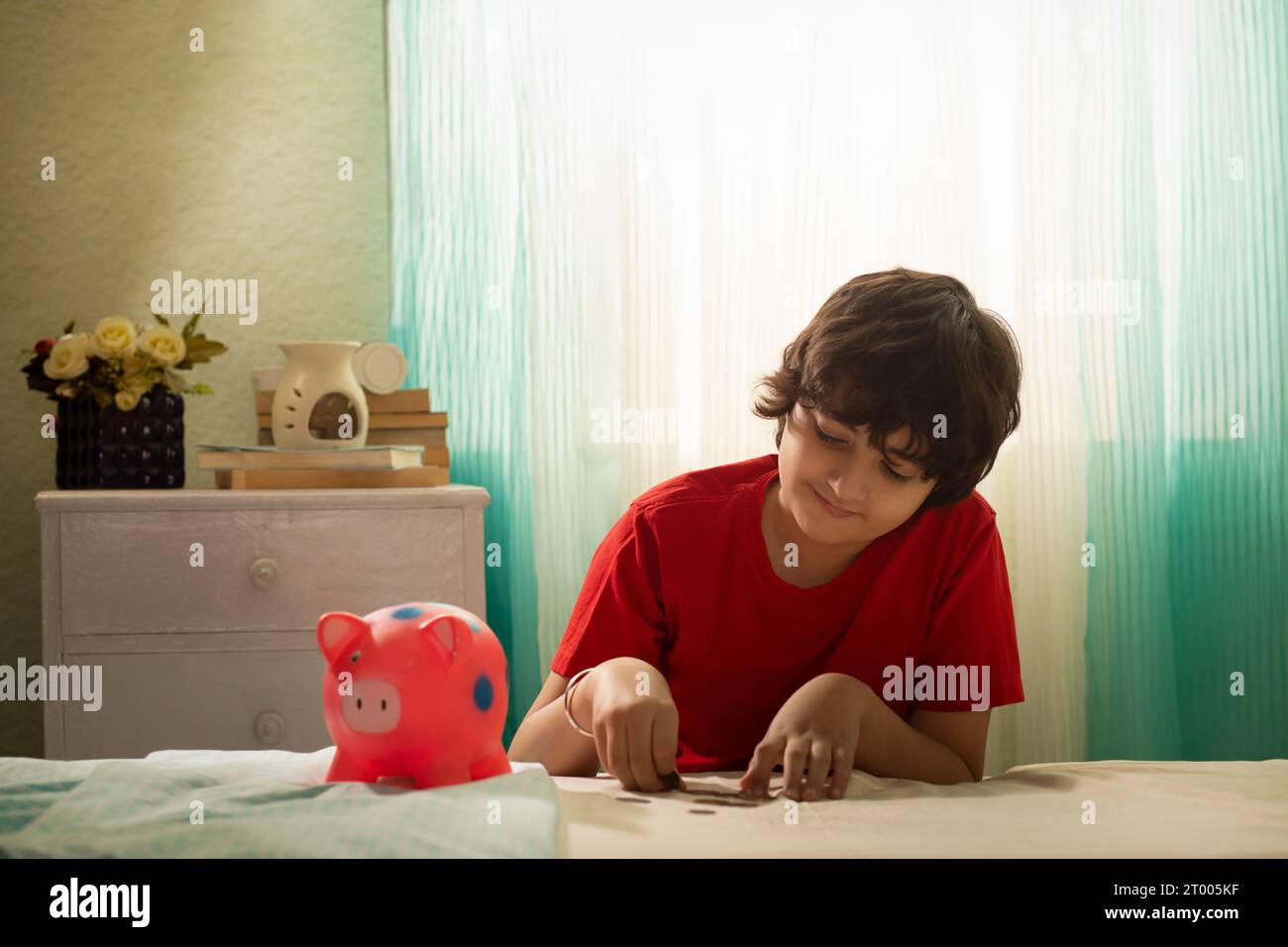 Boy putting coins into a piggy bank Stock Photo - Alamy