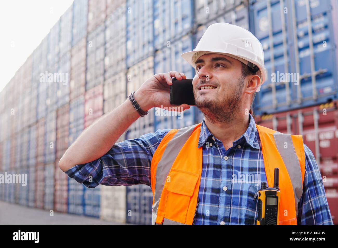 Young man container warehouse worker is making phone call at a shipping ...