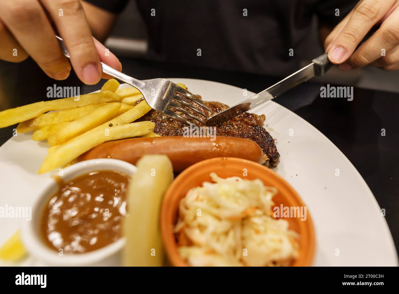 Man eating Grilled Meats stake from plate. hand holding knife and fork