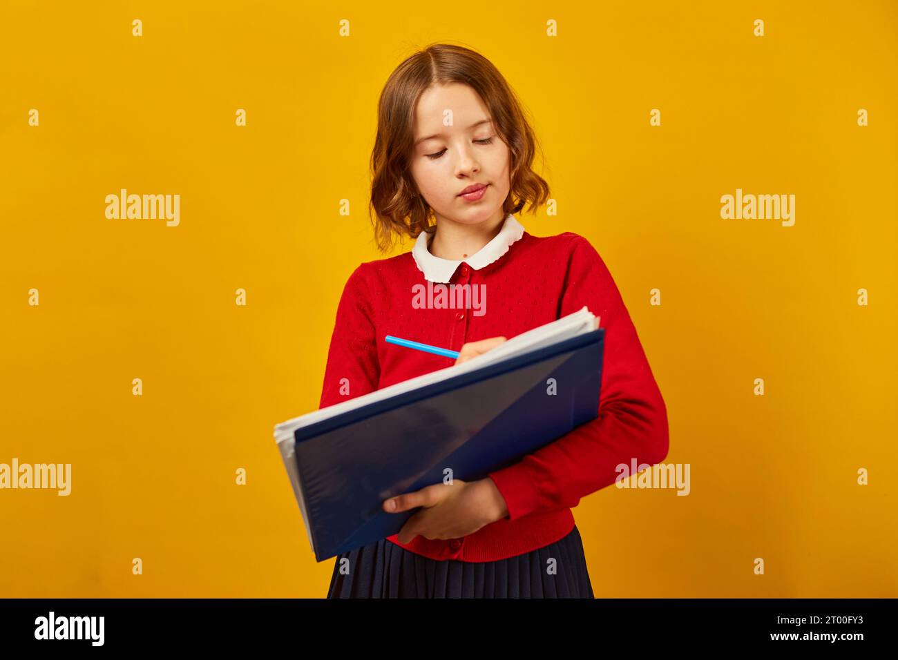 Thoughtful School teenage girl holding pen and write on notebook Stock ...