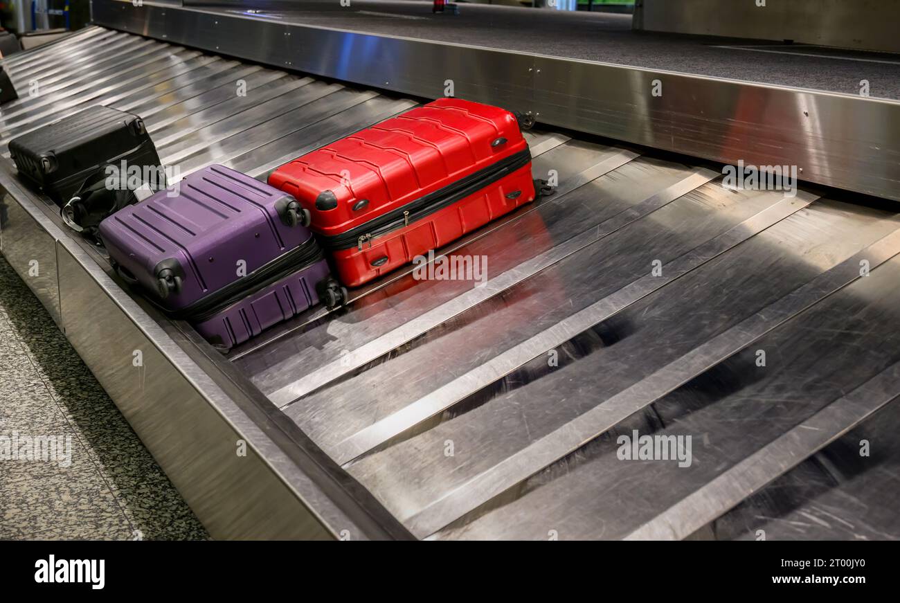 Baggages on luggage conveyor belt in baggage claim at airport. Stock Photo