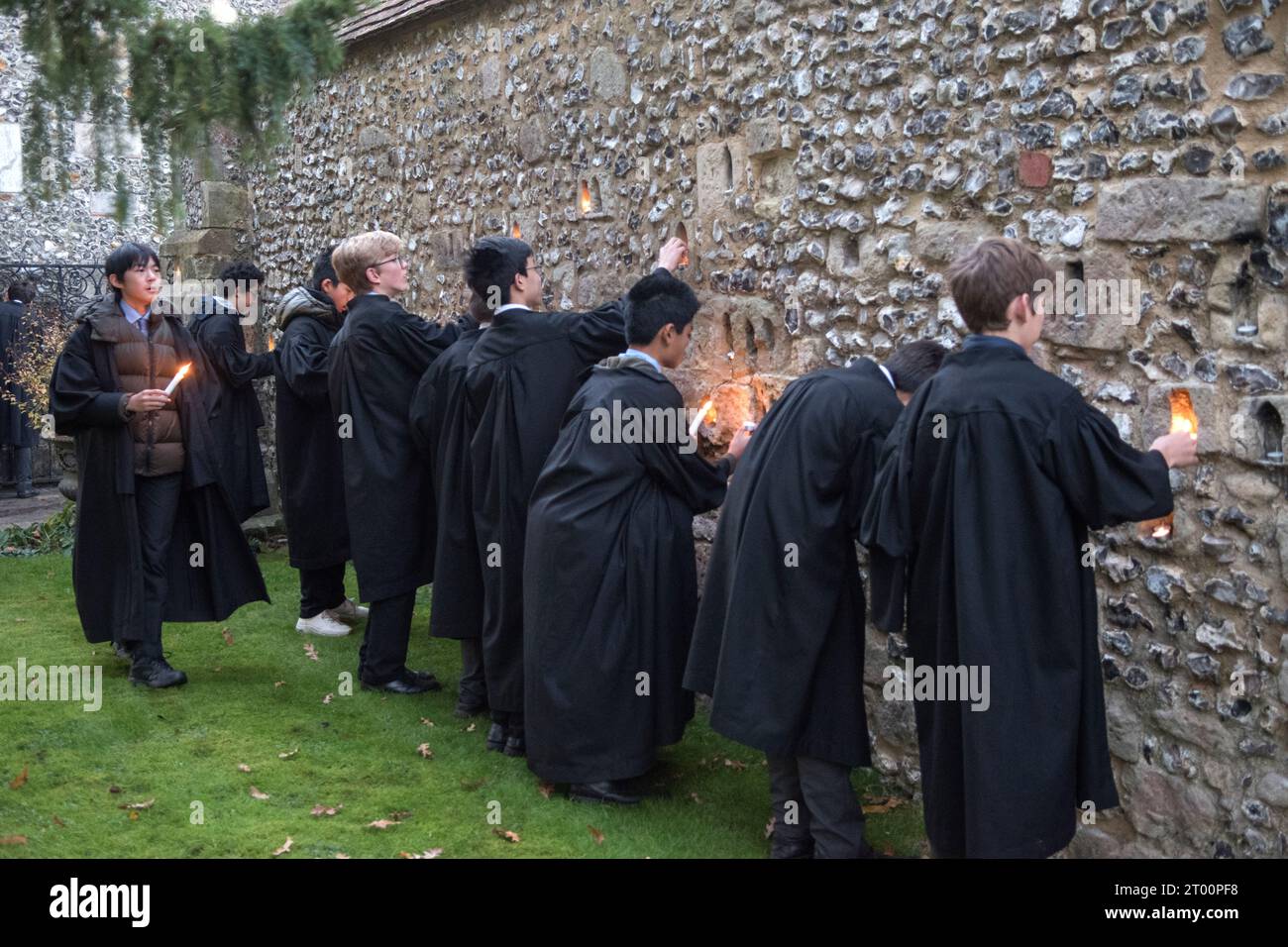 Winchester School Hampshire. Students at the annual Illumina Ceremony.  ‘College Junior Men’ these are students who are Scholars, light candles placed in niches in the medieval Meads wall. (The wall that surrounds a playing field.) Winchester, Hampshire, England  9th December 2022. HOMER SYKES. Stock Photo