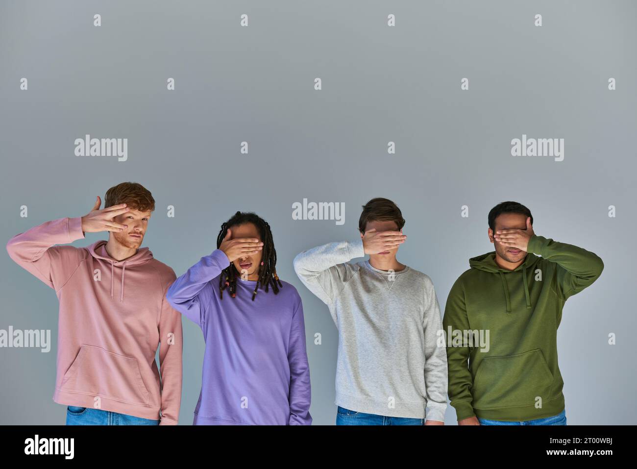 multicultural friends in urban wear closing eyes with palms one peeking looking at camera, diversity Stock Photo