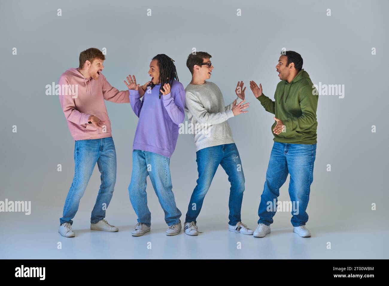 four cheerful surprised men in bright urban attires looking at each other, cultural diversity Stock Photo