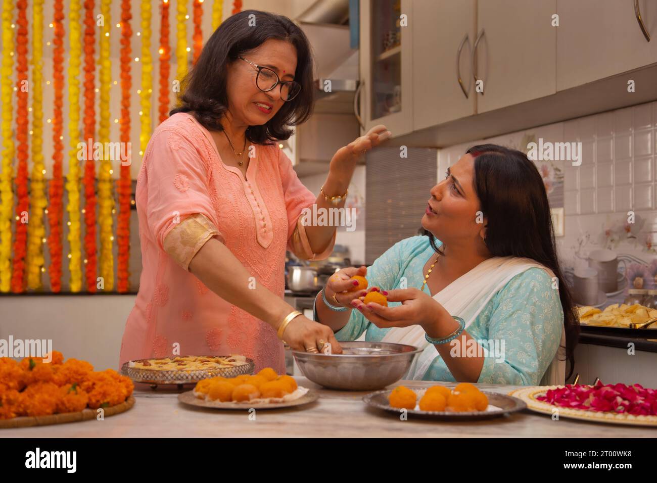 Mother in law teaching daughter in law how to make Ladoo on the occasion of Diwali Stock Photo