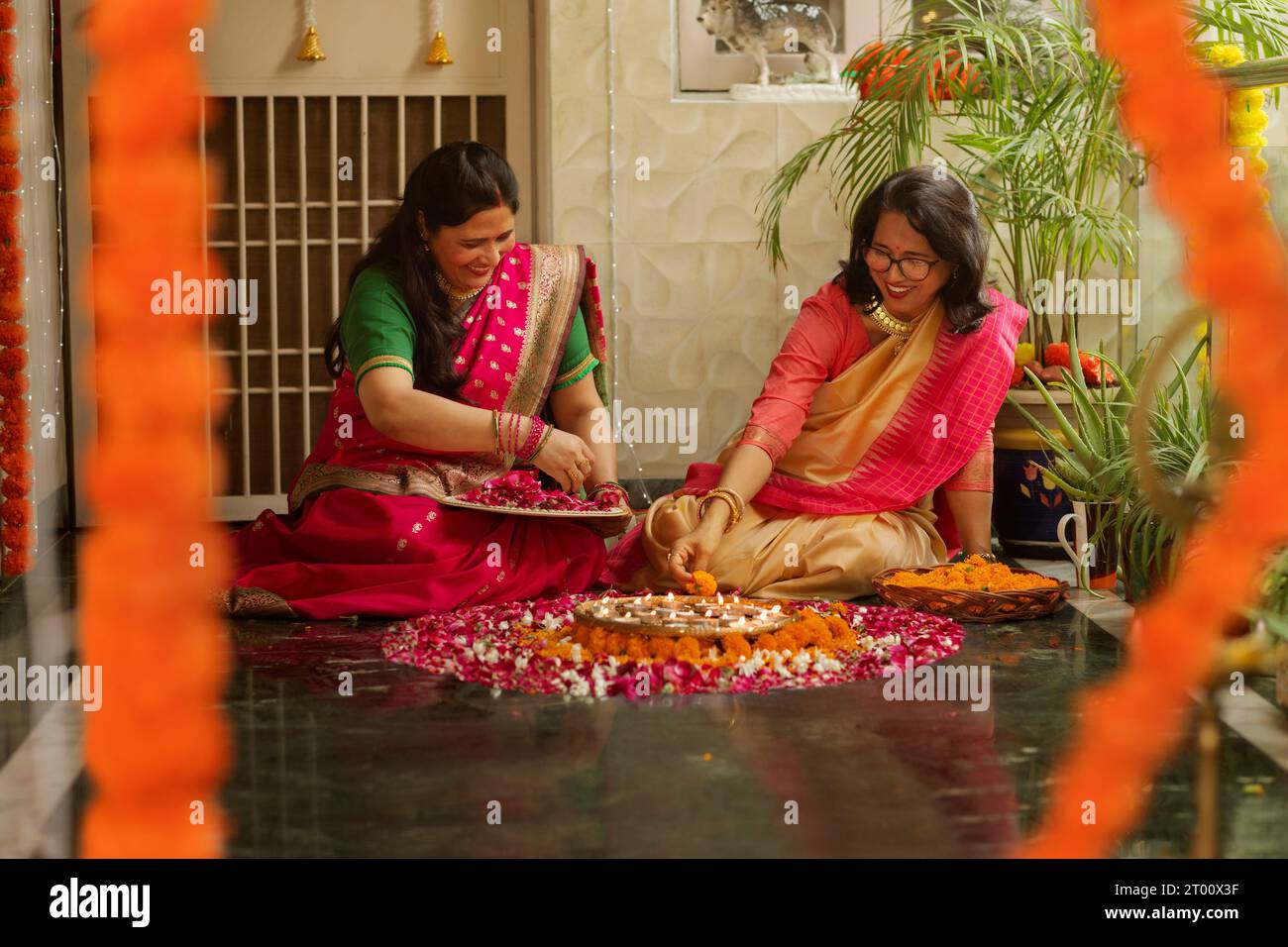 Mother-in-law and daughter-in-law decorating house with lamps and flowers on the occasion of Diwali Stock Photo