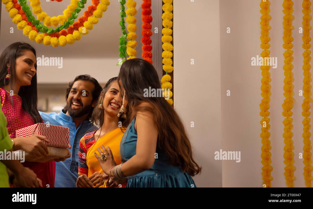 Cheerful excited and surprised couple welcoming and greeting friends  during  Diwali celebrations  at the entrance of their own home Stock Photo