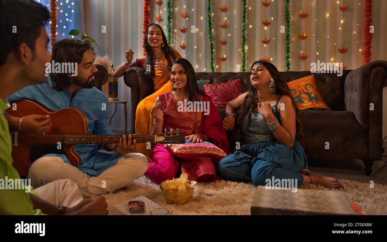 Friends celebrating Diwali together at home by singing Stock Photo