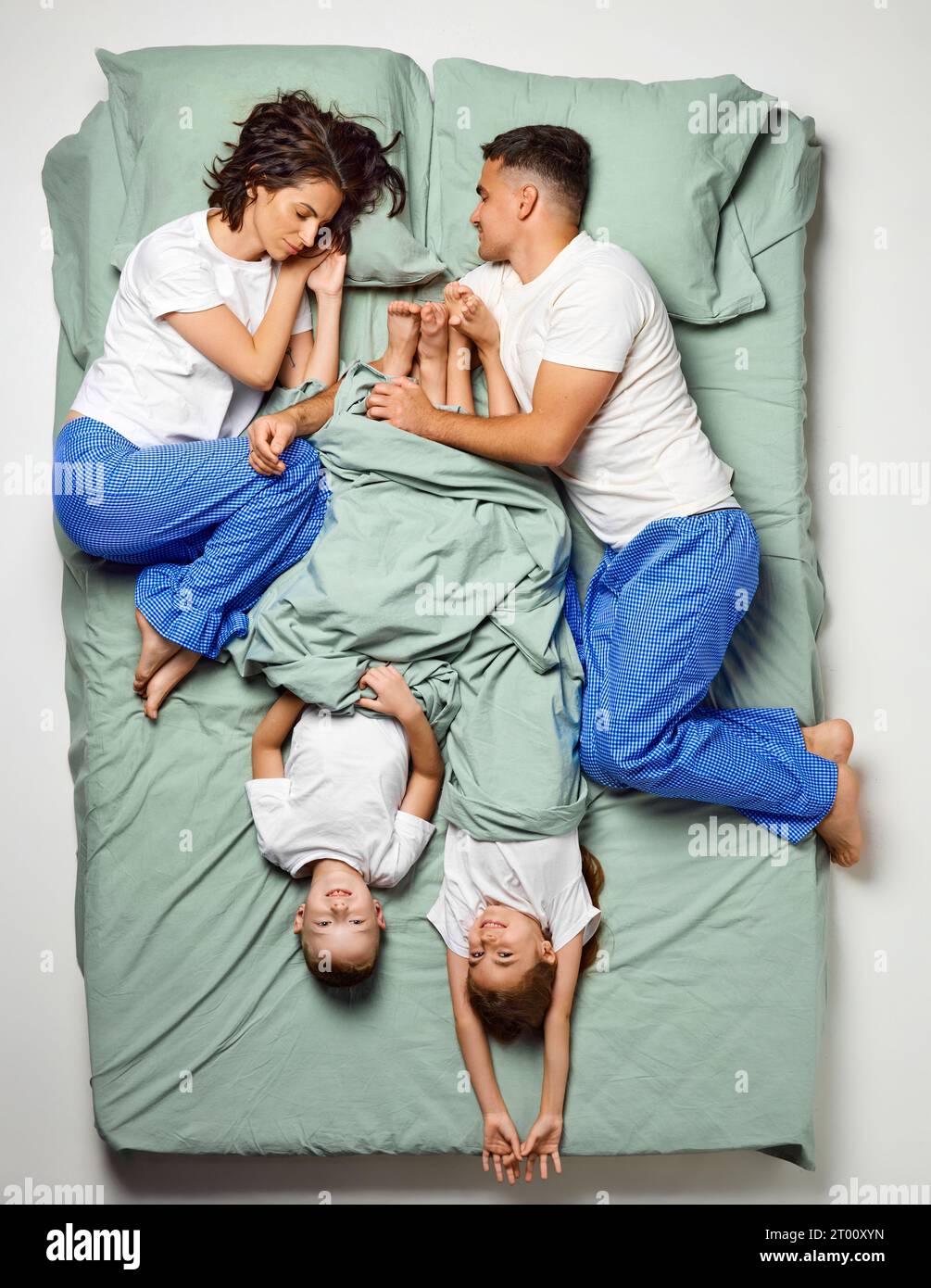 Top view portrait of people covered with blanket lying in bed. Children