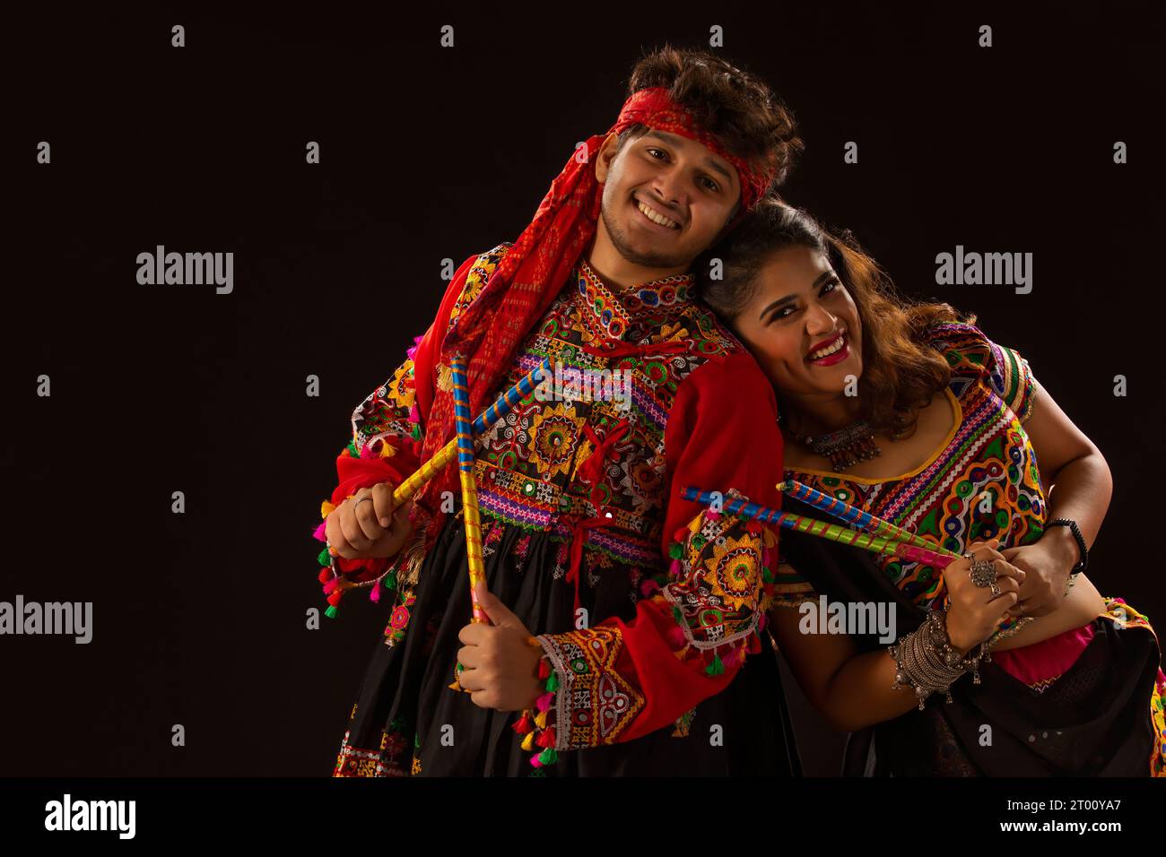 Portrait of happy young couple performing Dandiya Raas on a black ...