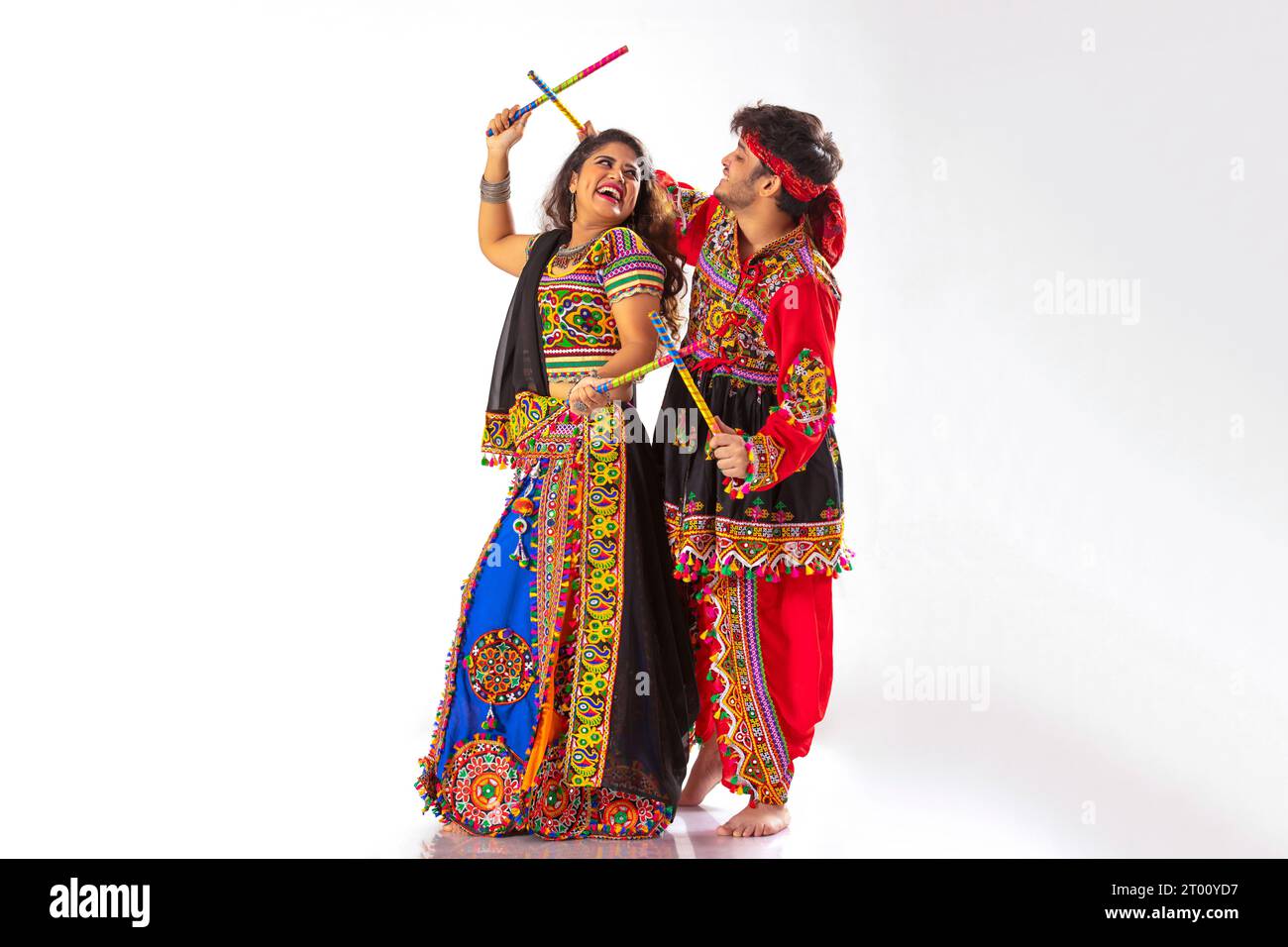 Portrait of happy young couple performing Dandiya Raas over white ...