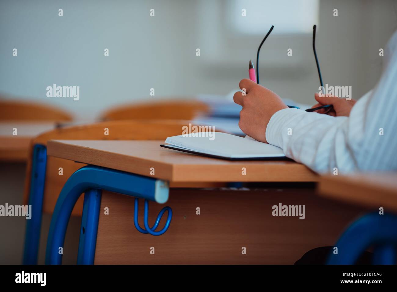 A close-up a student in a classroom holding glasses in her hand while ...
