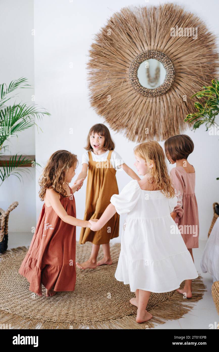 Four girls spinning around holding hands. Children play together, inside a bright house Stock Photo