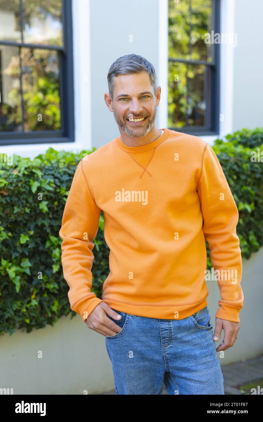 Happy caucasian man standing and smiling in front of house in sunny garden Stock Photo