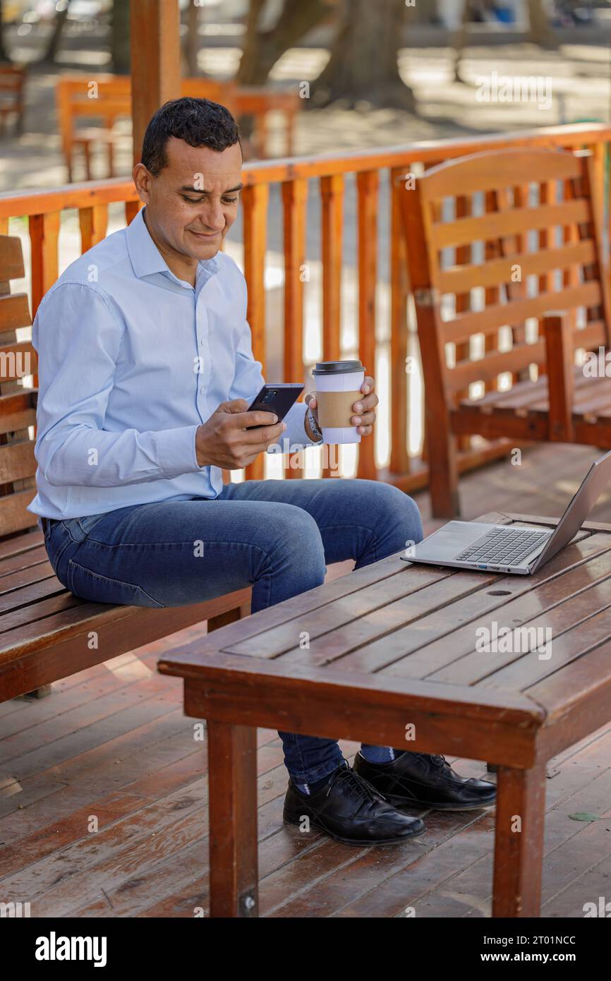 Latin man using a laptop while drinking coffee in a bar. Stock Photo