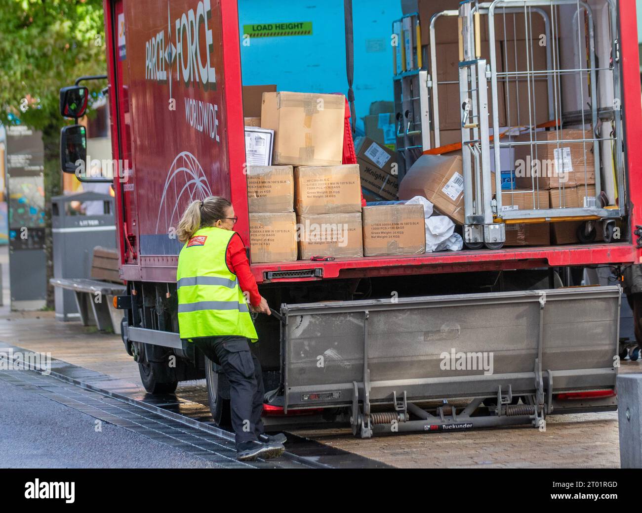 Woman postal worker closing tail-lift on Full laden Parcel Force ...