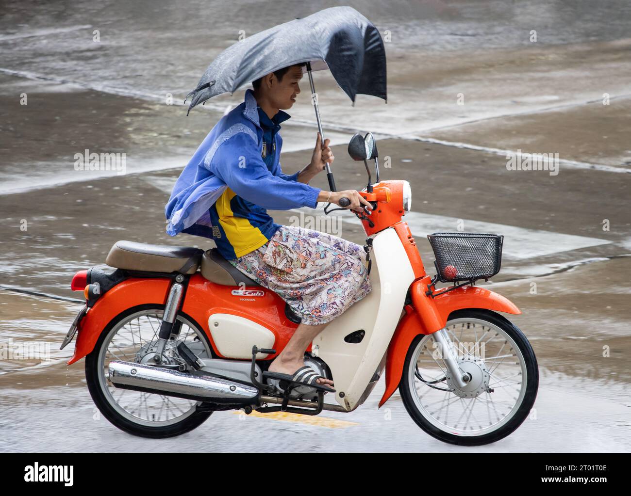 SAMUT PRAKAN, THAILAND, SEP 20 2023, A man with a umbrella rides a motorcycle in the rain Stock Photo