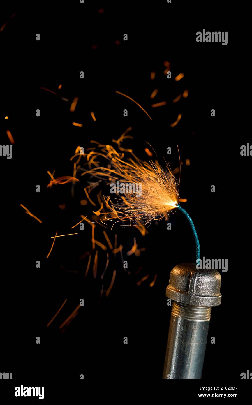 A Steel Pipe Bomb with lit fuse, sparks a flying, agaisnt a black