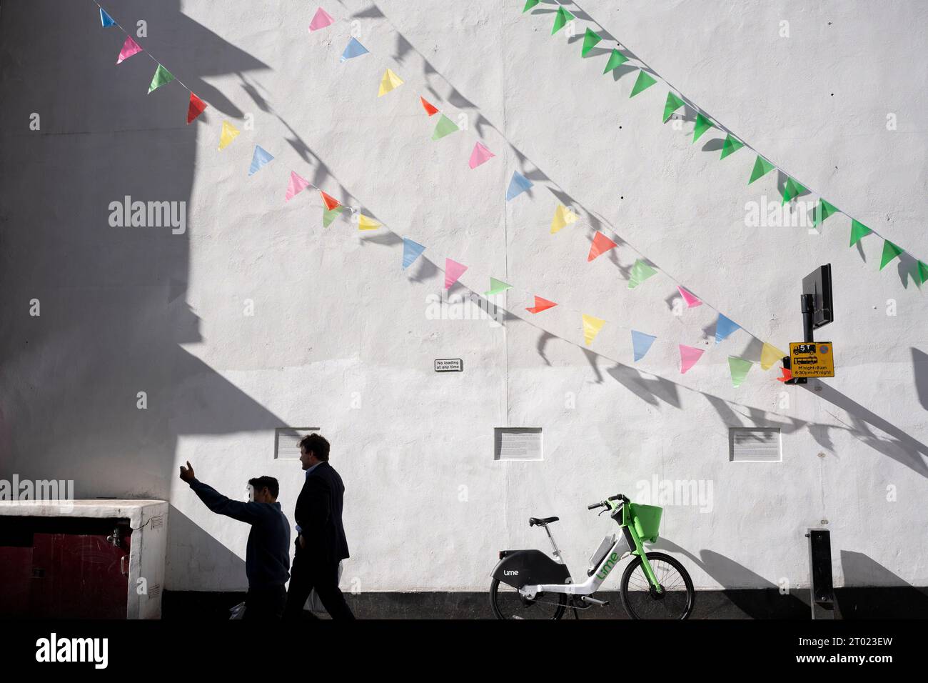Members of the public walk beneath triangular bunting in Bouverie