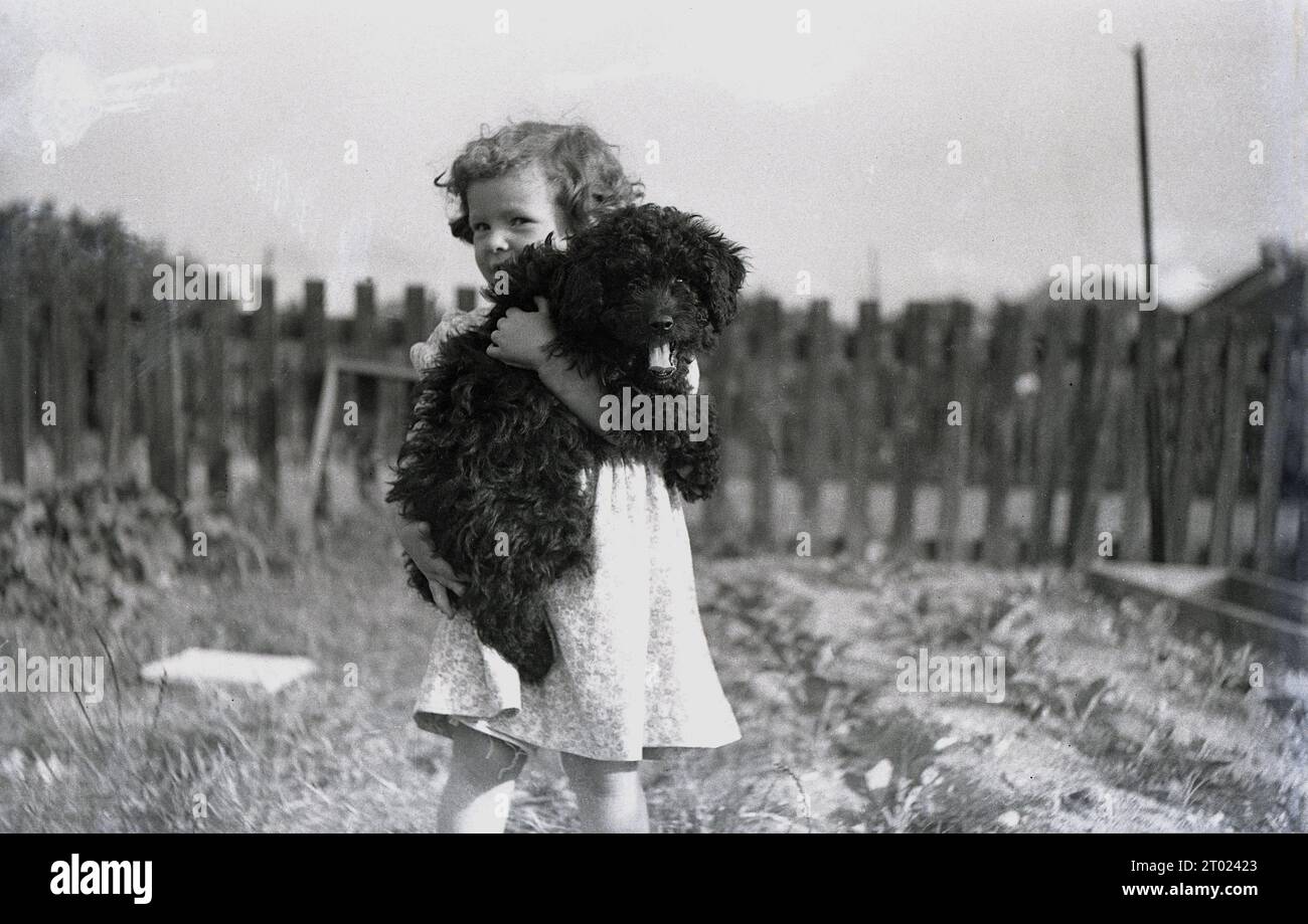 195s, historical, outside a young girl carrying her pet dog, England, UK. Stock Photo