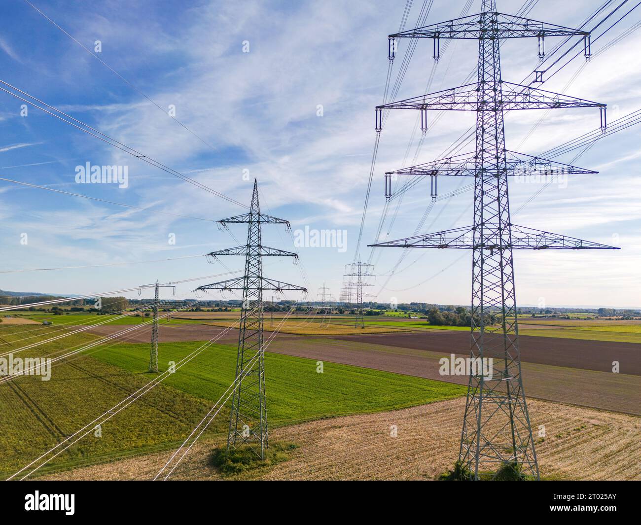 Aerial view of a row of high voltage pylons with many power lines in rural area to the horizon Stock Photo