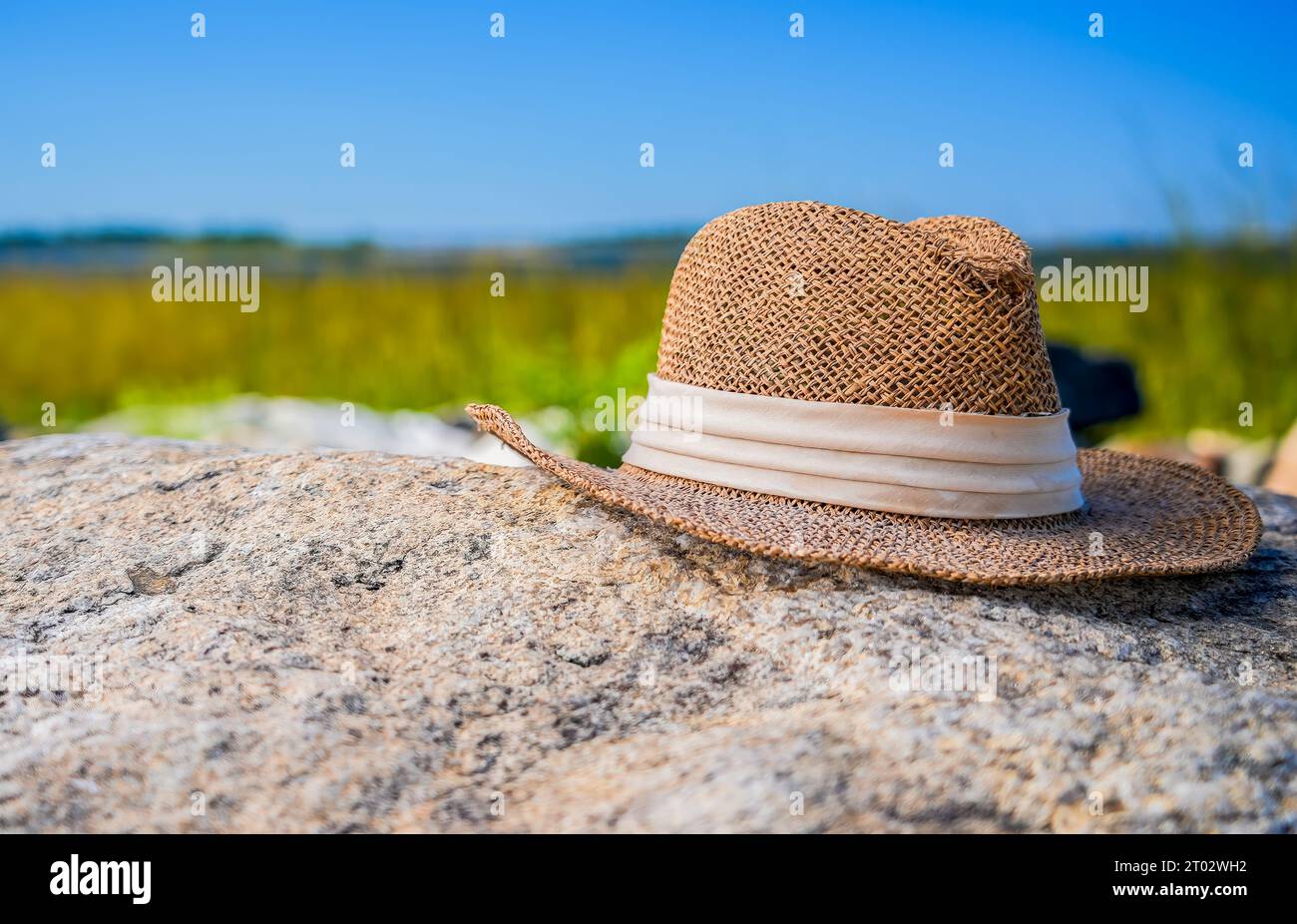 Straw hat on rock at beach in sunny day Stock Photo - Alamy