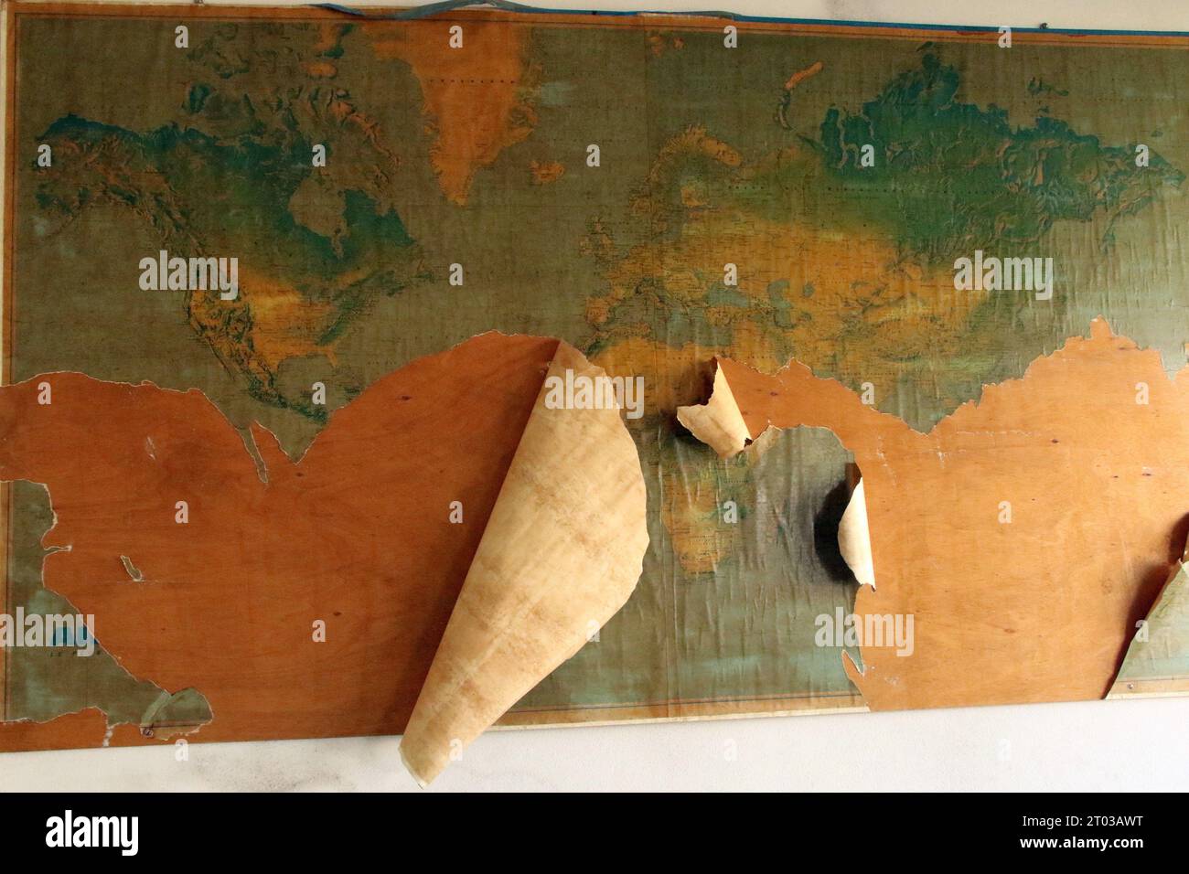 A stack of white paper cones rests on top of a cork bulletin board adorned with a vibrant world map illustration Stock Photo