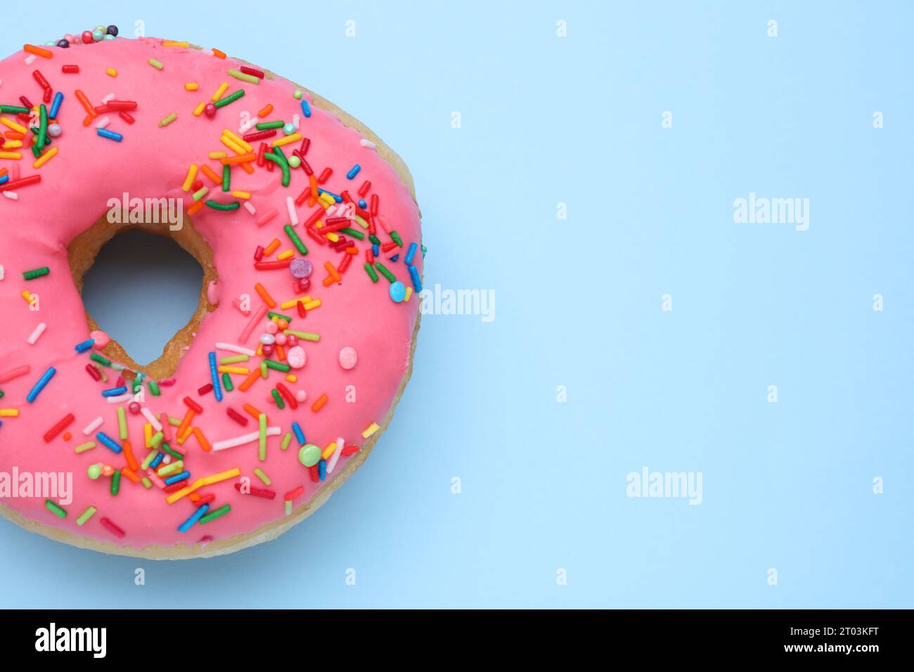 Glazed donut decorated with sprinkles on light blue background, top ...