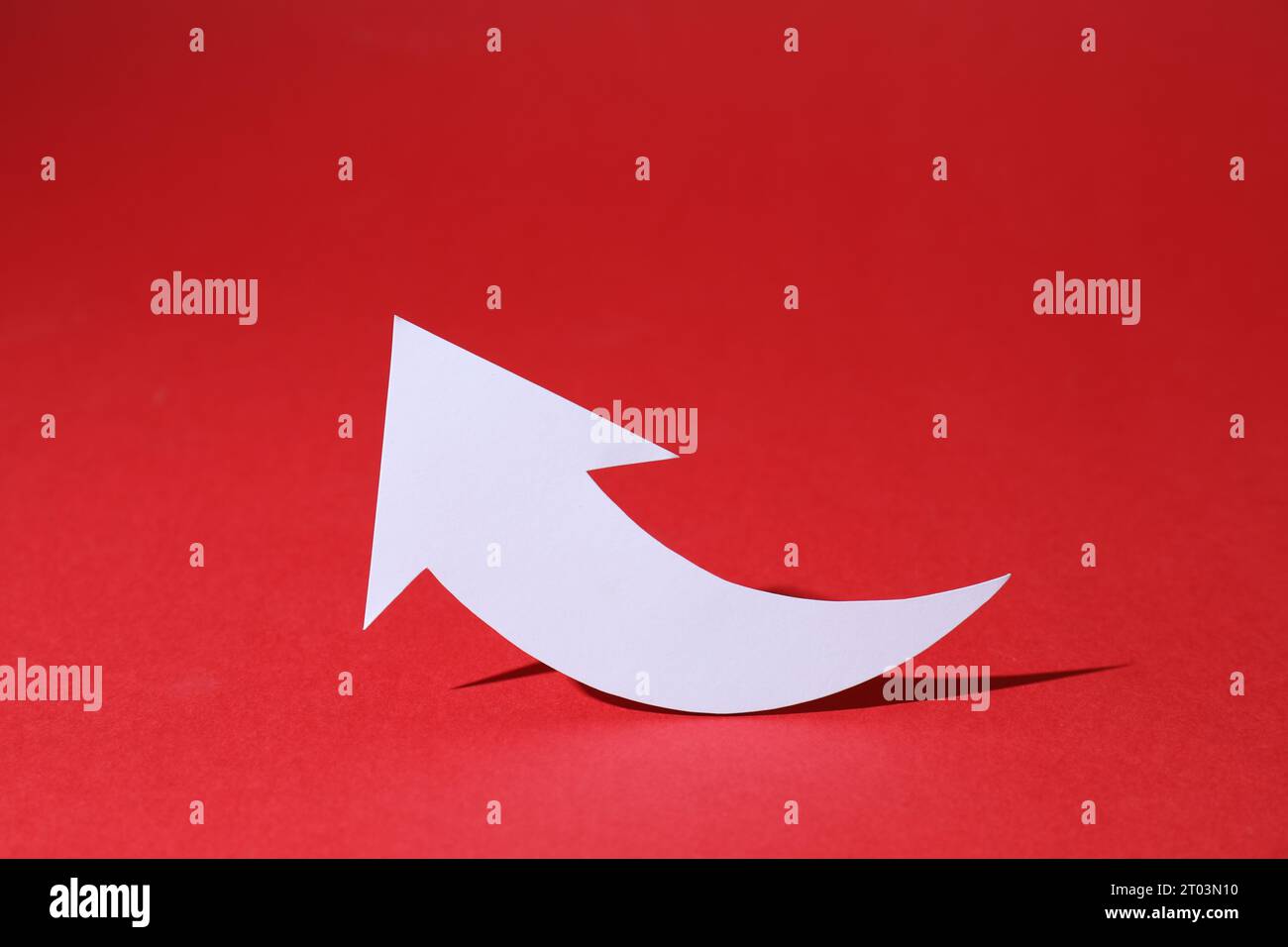 White curved paper arrow on red background Stock Photo