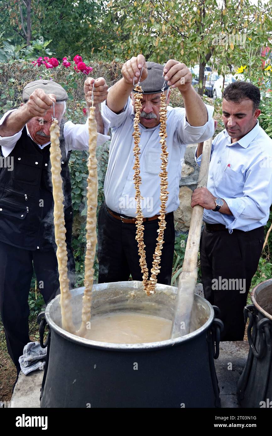 Diyarbakir, Turkey. 01st Oct, 2023. Three Kurdish villagers dip walnuts lined up on a rope into