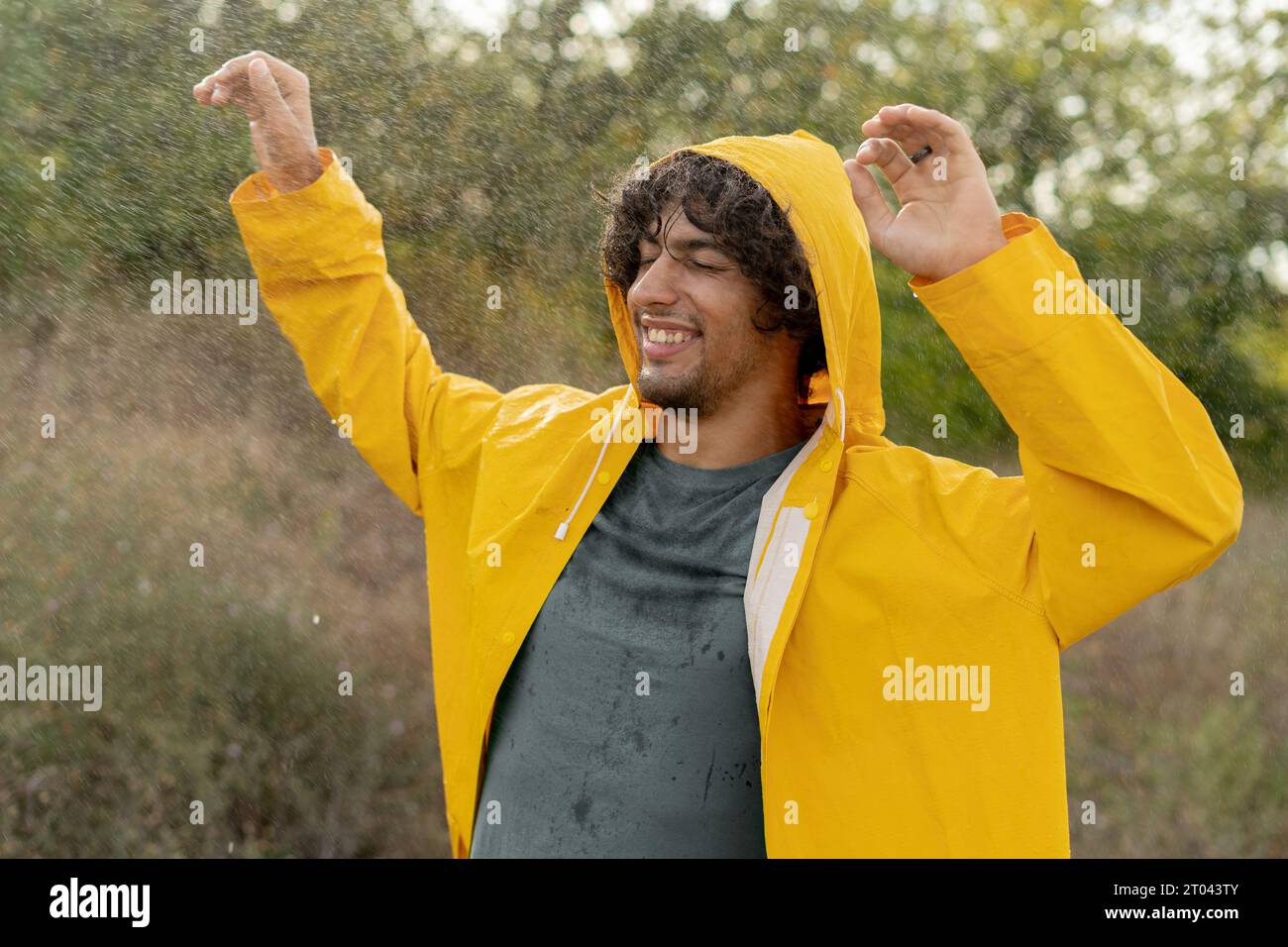 Joyful arabic guy enjoys his evening in the countryside by dancing in the rain. Playful young